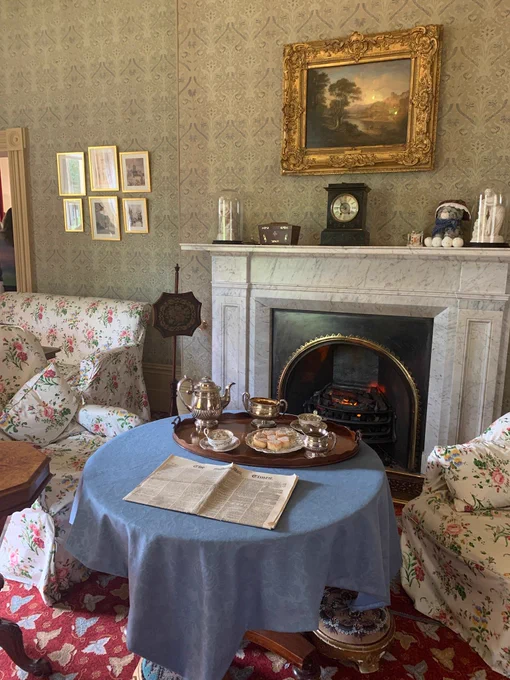 Elizabeth Gaskell's living room with a small table and newspaper on top.