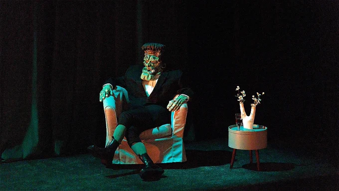A person dressed as Frankenstein's monster sits in a chair onstage