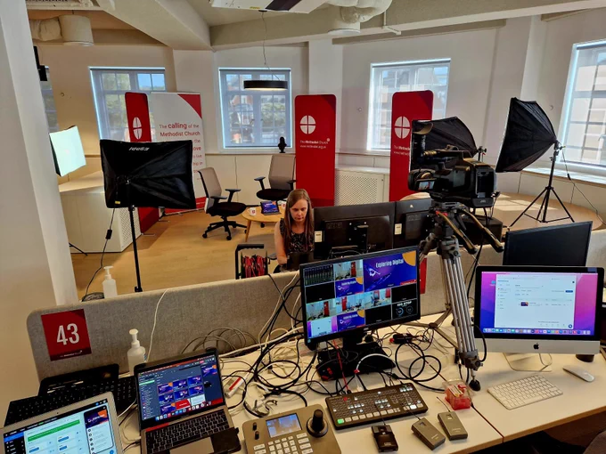A bank of computers set up with cameras and lights to stream the conference.