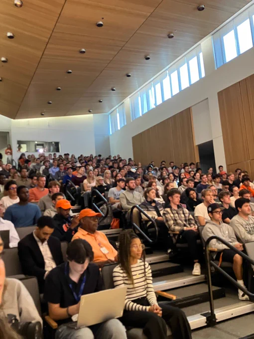 A Newhouse auditorium is filled with attendees listening to Bob Costas