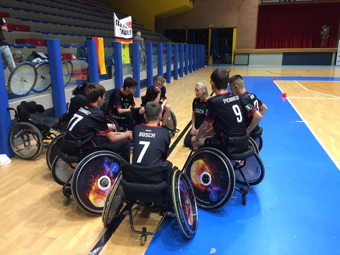 The team gathers around the coach at the WFDF 2023 World Wheelchair Ultimate Championships.
