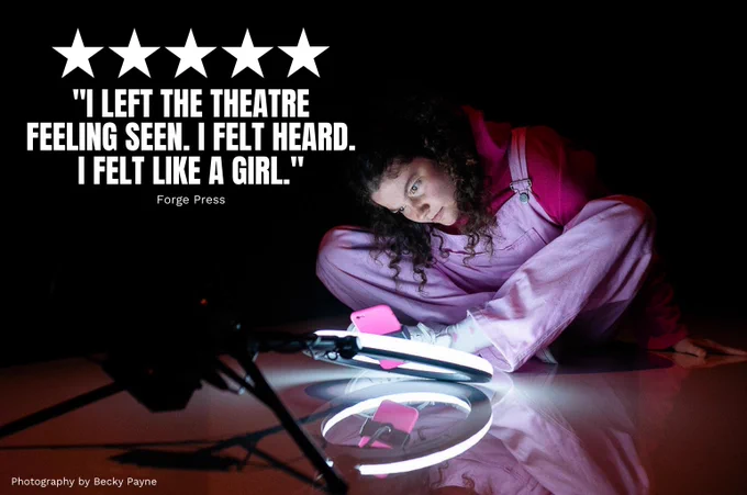 Alice Walker in We Could All Be Perfect. Photo by Becky Payne. A young woman sits in the dark and peers down at a phone which is set in a bring ring light. They wear pink dungarees and look curious.

Quote on top of the image reads FIVE STARS "I LEFT THE THEATRE FEELING SEEN. I FELT HEARD. I FELT LIKE A GIRL." (Forge Press)