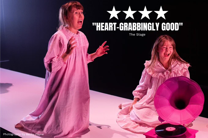 Rosa Hesmondhalgh and Heather Forster in We Could All Be Perfect. Photo by Becky Payne. Two young women wear Victorian night gowns and laugh and scream next to a bright pink gramophone. 

Quote on top of the image reads FIVE STARS "HEART-GRABBINGLY GOOD" (The Stage)