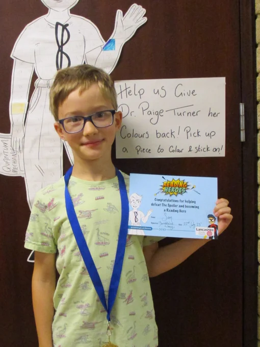 boy holding certificate. written notice in background reads help us give dr paige turner her colours back. Pick up a piece to colour and stick on