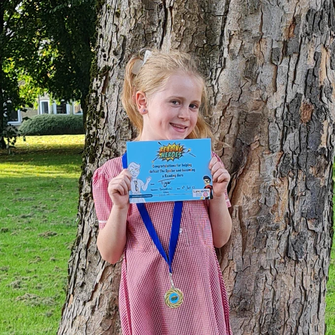 Girl with certificate and medal in front of tree