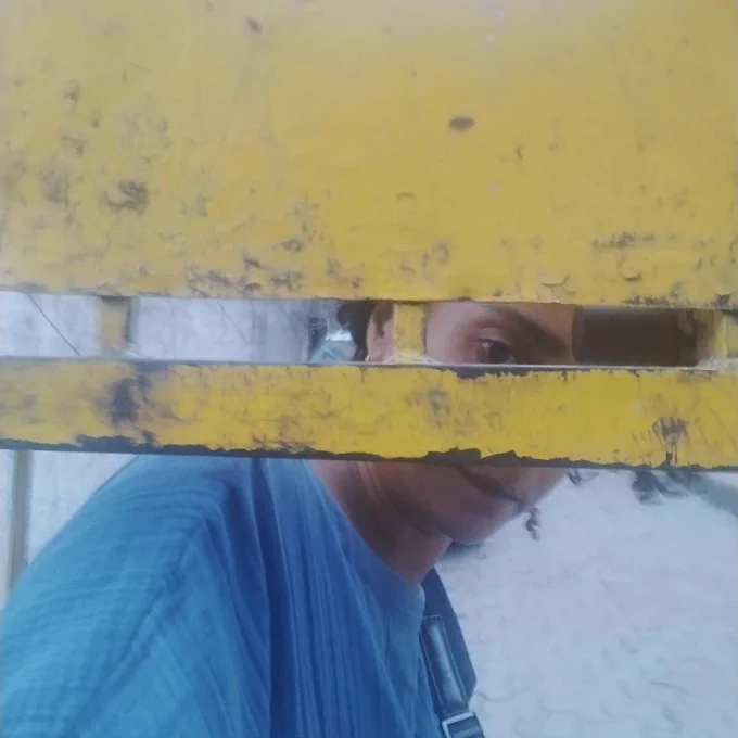 Image of Mridula Koshy behind a locked yellow gate, that illegally cuts off public access to the TCLP-South Extension Kotla library