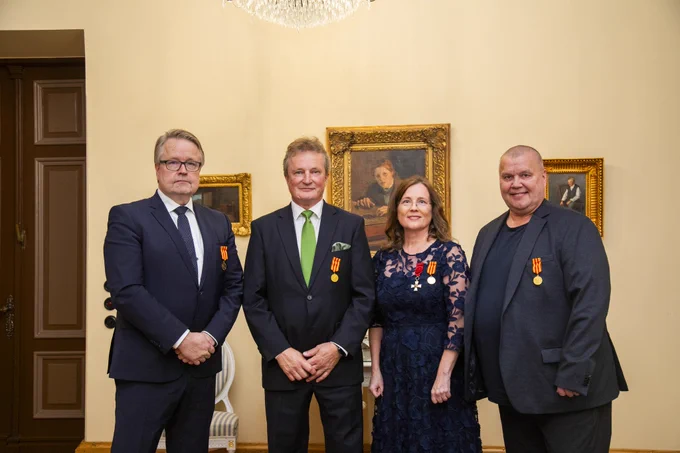 Neljä ansiomitalin saajaa rivissä.