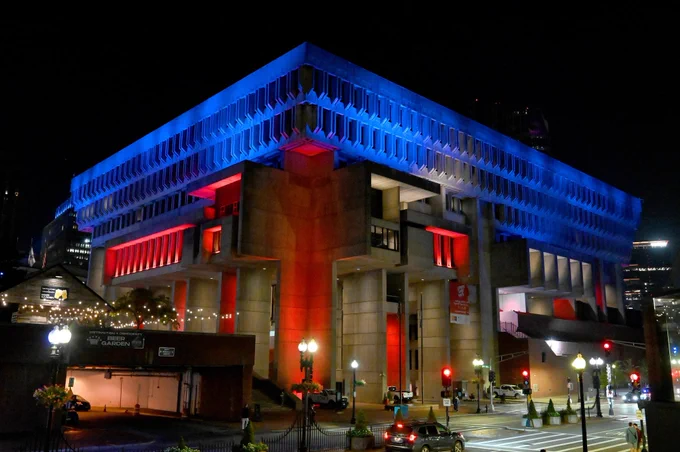 Boston City Hall photographed at night and lit in bright red and blue colors.