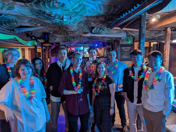 Group photo at the class, with everyone wearing florescent Hawaiian lei necklaces. 