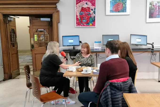 People sat around the table in York Explore Cafe, talking into an orange microphone