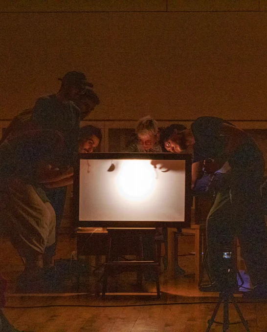 Audience members crowding around the shadow puppetry lightbox, adding figures to form a graphic score for Pia Rose Scattergood’s piece “Shadow Medley”