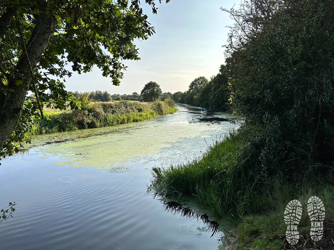 View over the River Rother, from the bank of the Royal Military Canal. Some canoeists in the distance gliding quietly along the calm waters