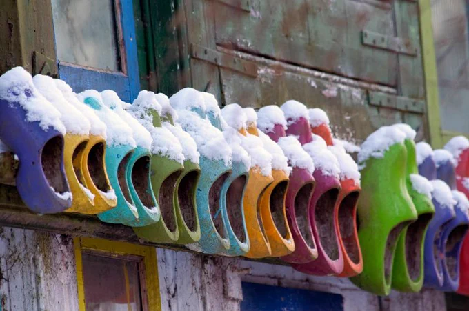 Colourful Clogs mounted to a wall, covered in snow to illustrate Winter in Amsterdam