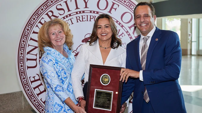 Monica receiving the award from President Harroz and Regent Shirley