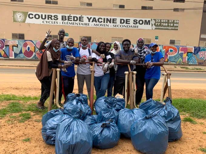 Group of YES Senegal Alumni pose in front of bags of trash they helped clean up