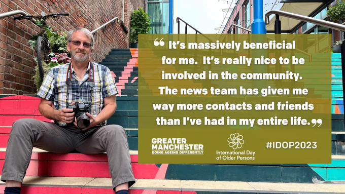 Person with a beard sitting on multicoloured steps holding a camera. Graphic text reads, ‘”It’s massively beneficial for me.  It’s really nice to be involved in the community. The news team has given me way more contacts and friends than I’ve had in my entire life.”’