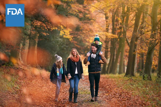 Family Walking Along Autumn Woodland Path With Father Carrying Son On Shoulders