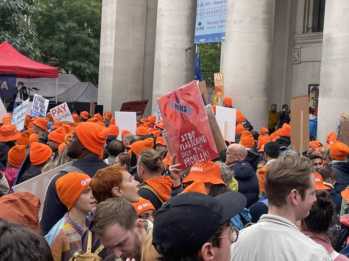 Image of junior doctors and consultants in Manchester with placards and orange BMA hats