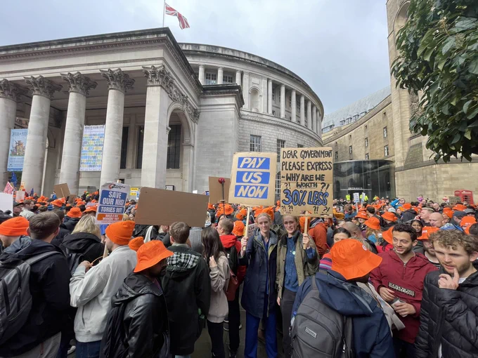 Image of junior doctors and consultants in Manchester with placards and orange BMA hats