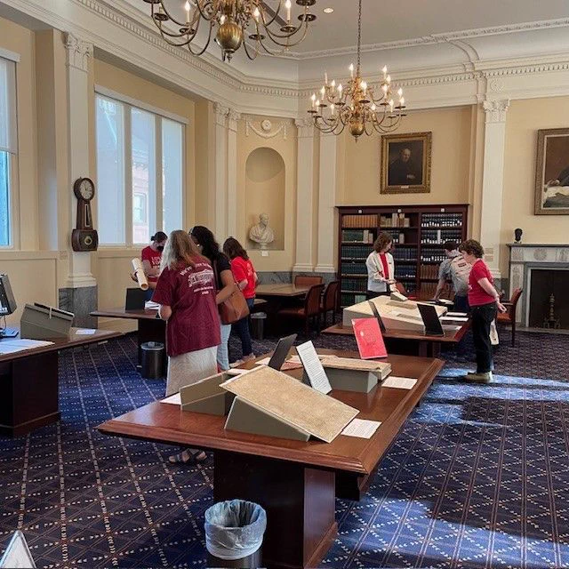  Students and library staff members view a display of rare books, manuscripts, and other unique materials in the Root Room, the Historical & Special Collections reading room.