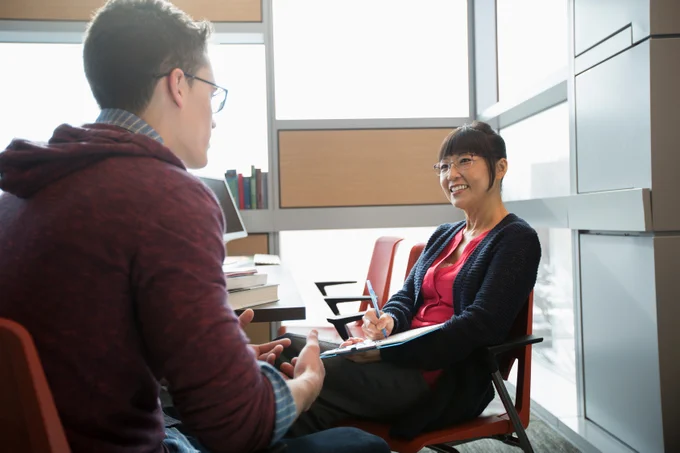 Photo of a counselor speaking with a young man.