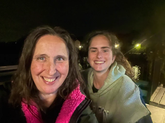 Photo of harriet and charlotte wearing dryrobes, on the Nemos Bar balcony in front of Stoney Cove quarry lake, leicestershire