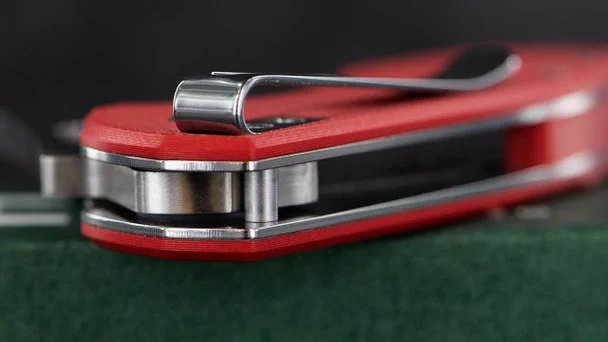 Picture showing the end of a UK legal folding pocket knife. The pocket knife has a deep carry pocket clip and red scales.