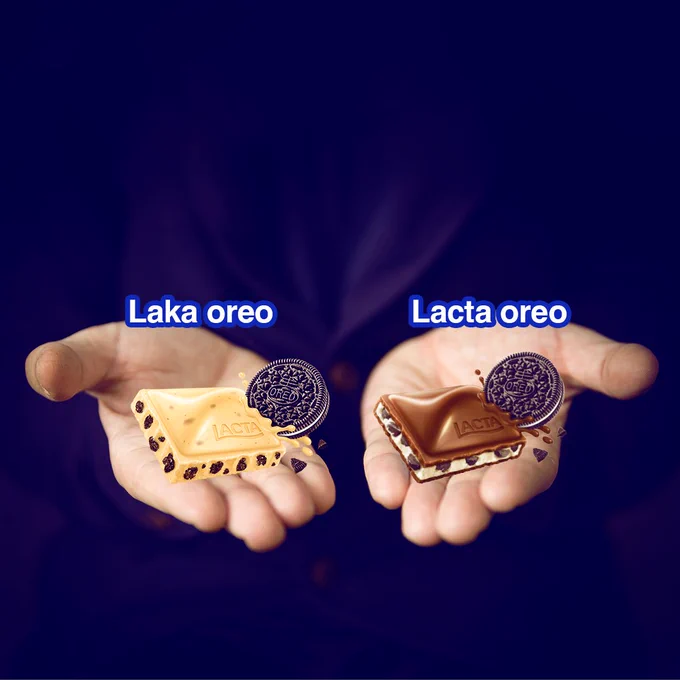 Imagem com fundo azul escuro e duas mãos abertas. A primeira, à esquerda, está segurando um quadradinho de Laka Oreo e a segunda um tabletinho de Lacta Oreo.​