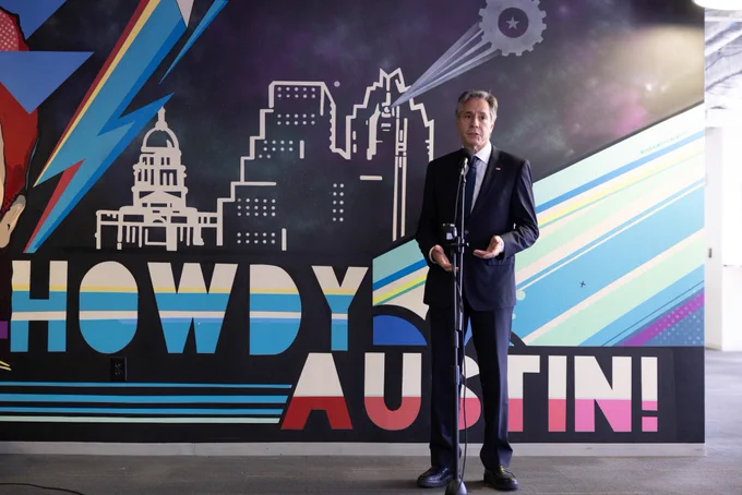 Secretary Blinken speaks to staff at Capital Factory in Austin, Texas. A Howdy Austin sign with the Austin skyline is behind him.