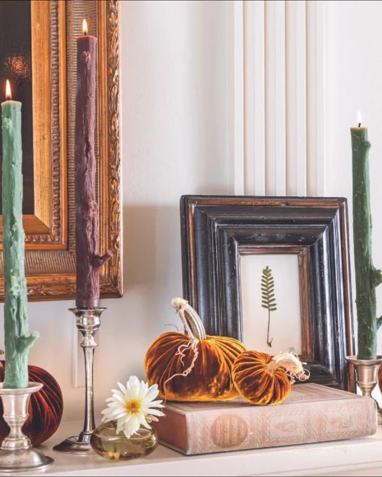 Third: A vignette of faux bois green and brown tapers in silver candlesticks, velvet pumpkins, an old book, and a pressed leaf in a wooden frame.