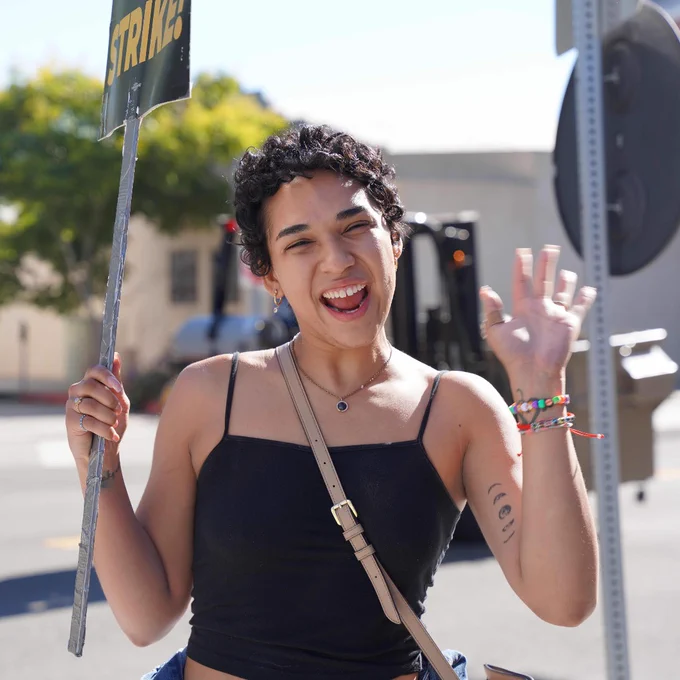 A person on the picket line waves at the camera.