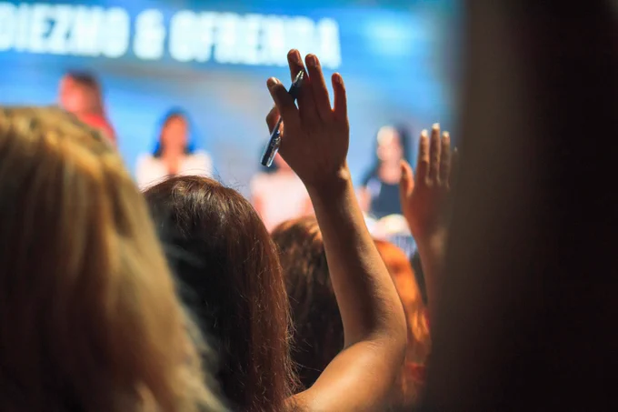 Person holding pen raising their hand.