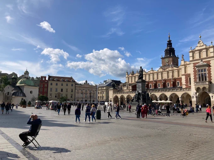 The central square of Krakow, a wide plaza with statues and historical buildings.