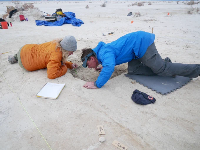 USGS scientists Kathleen Springer and Jeff Pigati work at the White Sands site, lying on the ground with their faces close to the ground.

Photo credit: NPS