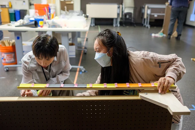 Two women measuring a plank