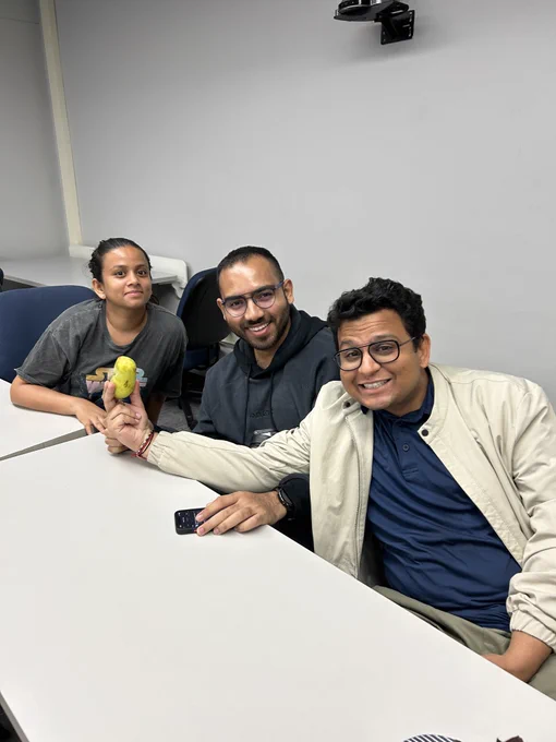 Three PAWS members holding a paw paw fruit between them. A paw paw is a small greenish yellow fruit similar to a banana with large black seeds inside. They grow in damp and dark conditions. 