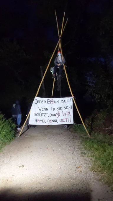 Menschen auf Tripod. Banner-Aufschrift Jeder Baum zählt. Wenn ihr sie nicht schützt, dann wir Hambi, Danni, Dieti!