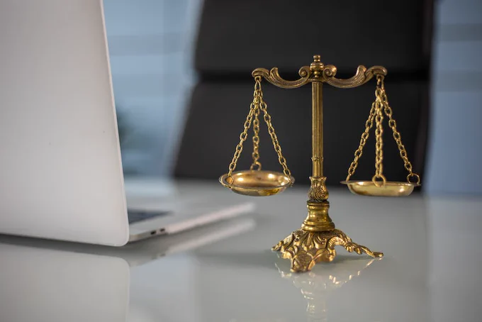 A Golden Balance Scale beside a Laptop
