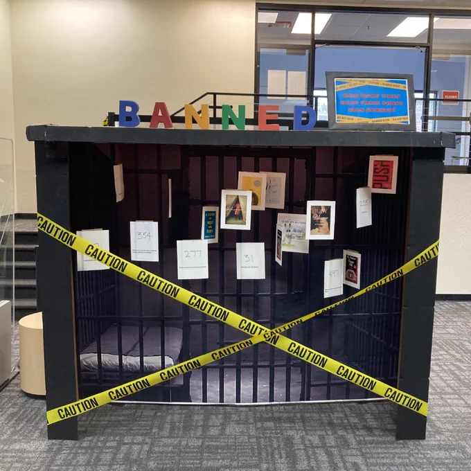 Photo two shows a jail cell display showing banned and challenged books on the bars of the cell, with caution tape blocking them. 