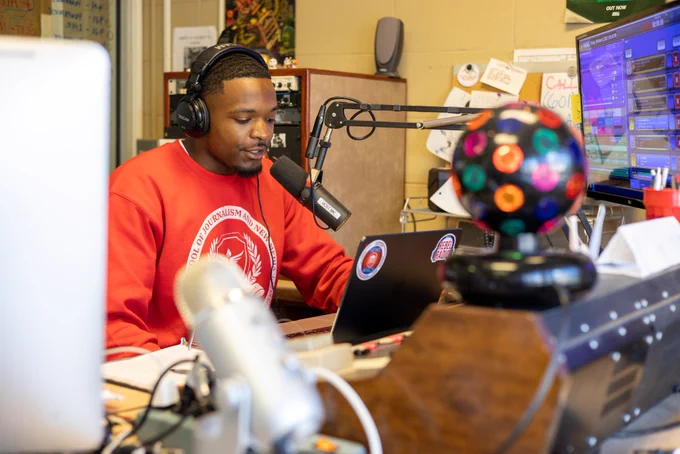 A student sits in the radio booth discussing music and news.