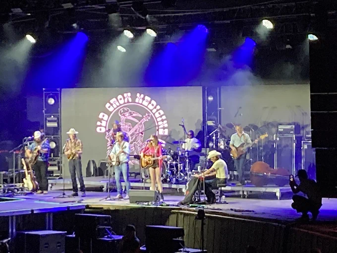 Molly Tuttle stands center stage singing and playing acoustic guitar with Old Crow Medicine Show at the Monterey County Fairgrounds Arena for opening night of Rebels & Renegades 2023.