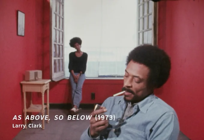 Scene from "As Above, So Below" depicting a man smoking in the foreground and a woman sitting by a window in the background.