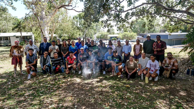 Group of people stand in the shade under a big tree