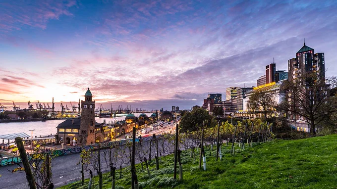 Foto: Zu sehen ist die Aussenansicht des Hotel Hafen Hamburg (rechts im Bild) an den Landungsbrücken (links im Bild) in Hamburg. (Quelle: Hotel Hafen Hamburg)