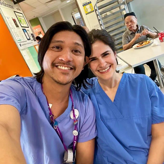 Shalom is a pictured taking a selfie alongside colleague and fellow nurse Sofia. They are both sitting in a ward cafeteria and wearing their nursing uniforms.