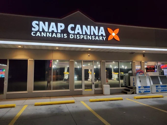 Snap Canna Dispensary in Pontiac, IL at night. Reflection in the windows shows gas pumps.