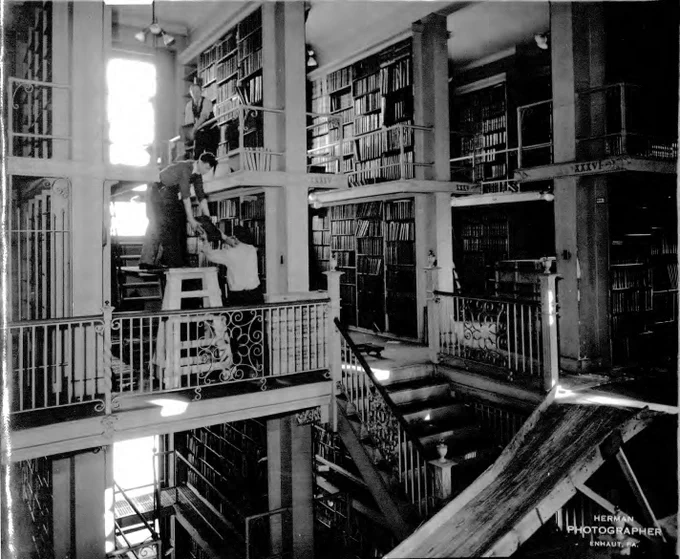 Individuals work in the State Library to add books to the bookshelves. 