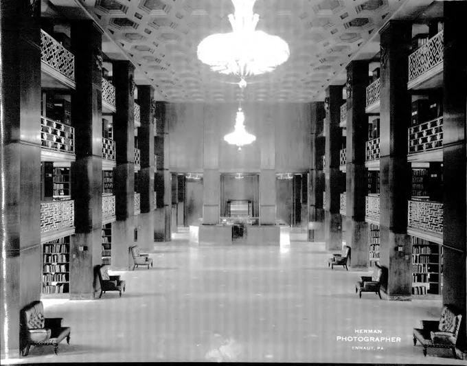 The state library sits empty with a full view of the bookcases, seating, and the circulation desk. 