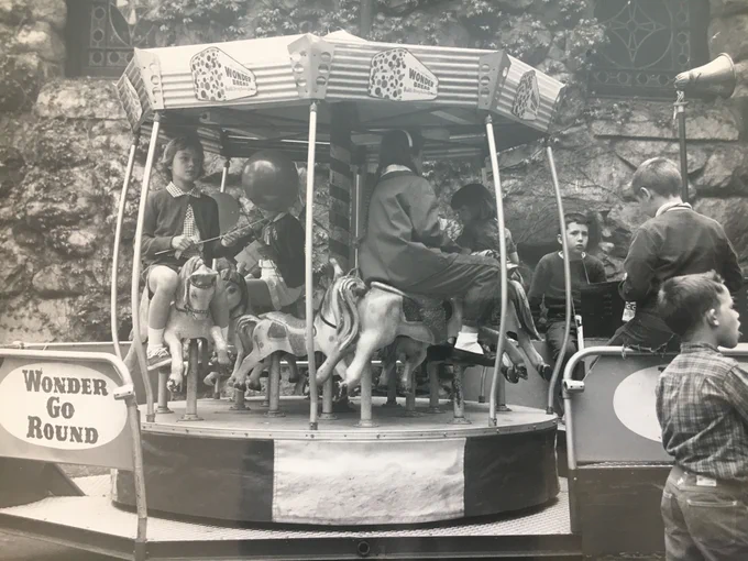 A group of children ride on a small Wonder Go-Round. 