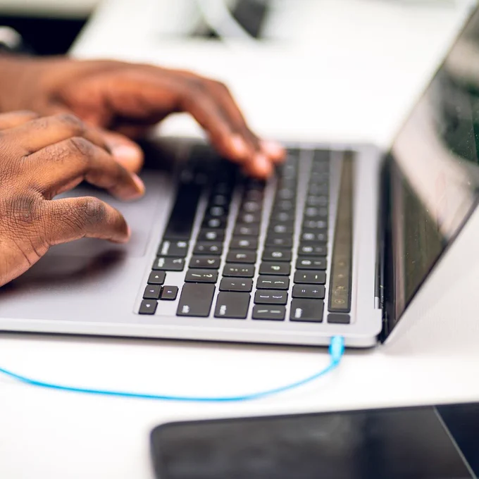 A person's hands typing on an open laptop.